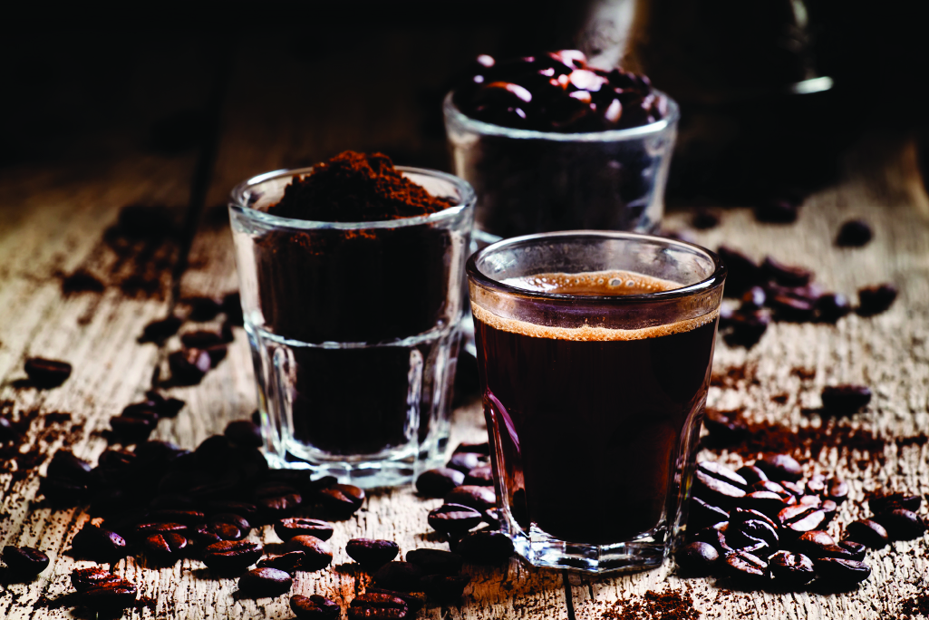close up of three shot glasses with coffee brewed, ground and beans